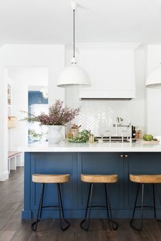 two stools are in front of an island with blue cabinets and white countertops