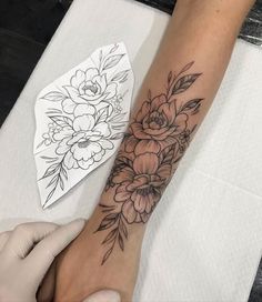 a woman's arm with flowers on it and a piece of paper next to it