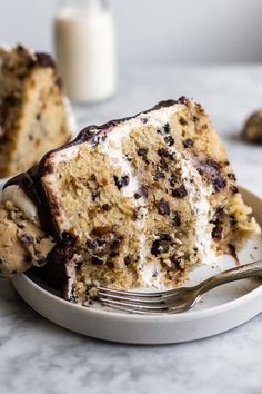 a piece of cake on a plate with a fork and some milk in the background