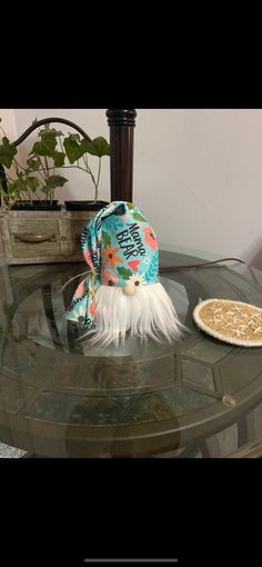 a small hat sitting on top of a glass table next to a pizza crust and potted plant