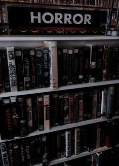 a book shelf filled with lots of books next to a sign that says horror on it