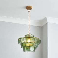 a green chandelier hanging from the ceiling in a room with white walls and flooring