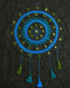 a blue and green crochet doily with tassels hanging from it