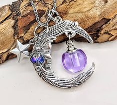 a necklace with a purple glass ball hanging from it's side next to a star