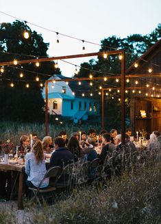 a group of people sitting at a dinner table in the middle of an open field