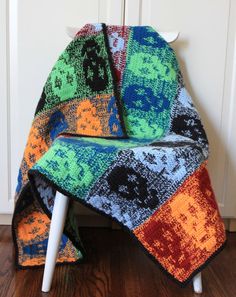 a multicolored blanket sitting on top of a wooden floor next to a white chair