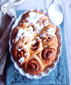 cinnamon rolls with icing on a plate next to a spoon