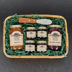 four jars of jam in a basket with a knife