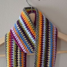 a multicolored crocheted scarf hanging on a coat rack