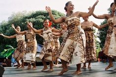 a group of women in native dress dancing on a stage with their hands up to the sky