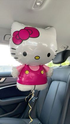 a hello kitty balloon sitting in the back seat of a car