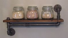 three mason jars are sitting on a shelf with pipe fittings in the bottom, and one is filled with sand