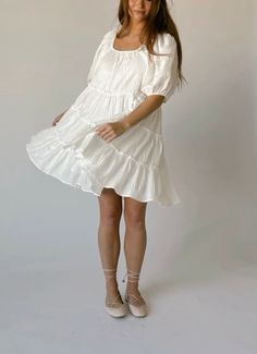 a woman in a white dress posing for the camera with her hands on her hips