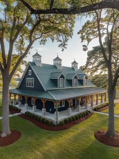 a large blue house sitting in the middle of a lush green field with lots of trees