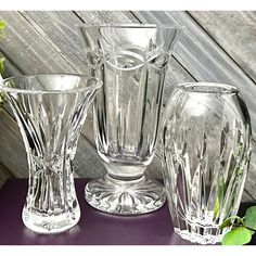 four glass vases sitting on top of a purple table