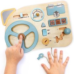 a child's hand is pressing buttons on a wooden toy