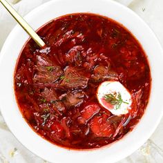 a white bowl filled with beef and red wine soup on top of a marble table