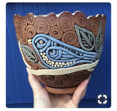 a hand holding up a ceramic bowl with designs on it