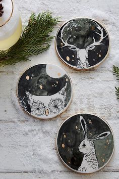 three coasters decorated with black and white designs, one has an image of a deer on it