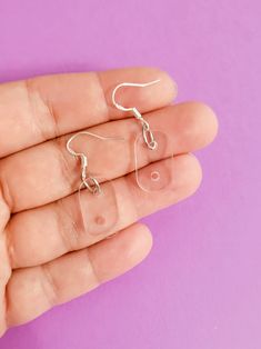 a person is holding some type of earring in their hand on a purple background