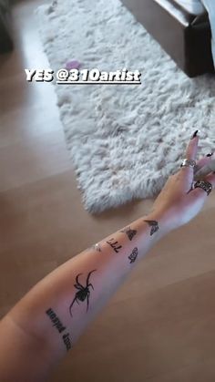 a woman's arm with tattoos on it in front of a bed and rug