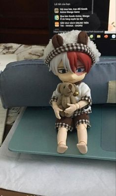 a doll sitting on top of a laptop computer