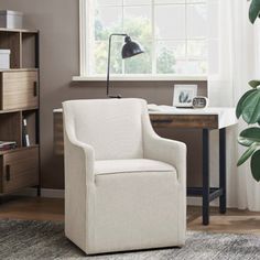 a white chair sitting in front of a window next to a book shelf and desk