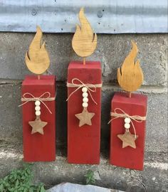 three red candles with wooden decorations on them