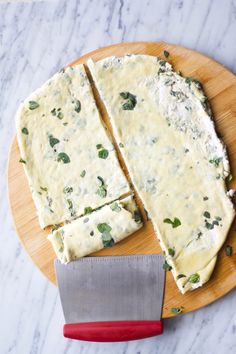 cheese and spinach spread on top of a wooden cutting board with a knife next to it