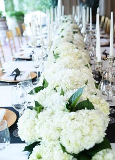 a long table with white flowers and candles