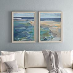 two paintings hang on the wall above a white couch in a living room with blue walls