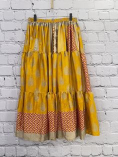 Twirl the day away in this gorgeous, buttery soft skirt. The long, full design is flattering to every shape. Made of vintage rasgulla silk saris. Each piece will be unique. Available in 2 sizes S/M 4-10 L/XL 12-18 Approximately 38” long Care Instructions: Hand wash and line dry for longest life. Disclaimer: The material used in this style is repurposed, vintage material. Small imperfections may be present. Fabrics may have small threads or holes in the layers. Small stains may be found. Traditional Tiered Sharara For Diwali, Bohemian Block Print Sharara For Navratri, Traditional Tiered Skirt Dress With Zari Work, Bohemian Maxi Length Dupatta For Diwali, Bohemian Maxi Dupatta For Diwali, Traditional Dresses With Zari Work And Tiered Skirt, Traditional Festive Sharara With Tiered Skirt, Traditional Zari Work Tiered Dress, Bohemian Block Print Sharara For Festive Occasions