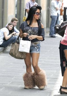 a woman walking down the street with her handbag on her hip, in front of people