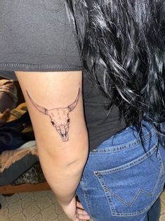 a woman's arm with a bull skull tattoo on the back of her left arm