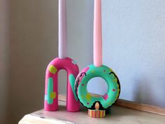 two candles, one pink and one green with donuts on them