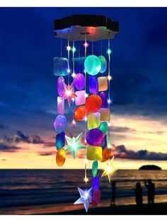 a wind chime hanging from the side of a beach next to the ocean at night