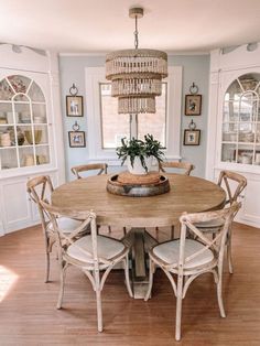 a dining room table with four chairs and a chandelier hanging from the ceiling