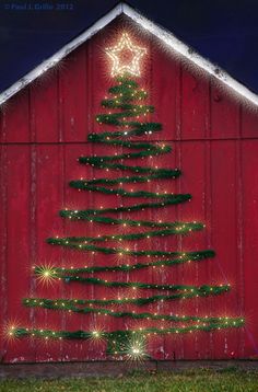 a red barn with a christmas tree on the side and lights in the shape of stars