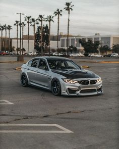 a silver car parked in a parking lot next to palm trees