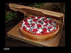 a pizza in a box with cherries on it sitting on a table next to some plants