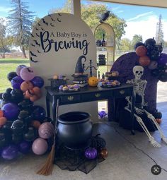 a table with halloween decorations and balloons in front of a sign that says a baby boy is brewing