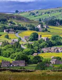 the countryside is full of houses and green fields with yellow flowers in bloom on the hillside