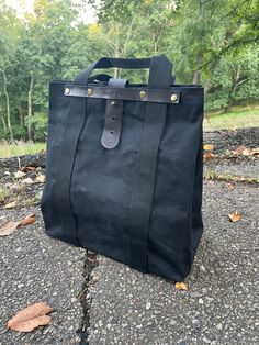 Black waxed canvas tote bag (12.5" x 14" x 7") Polyester straps (1.5") Leather bottom and supports for handle straps. Coated Canvas Bag With Reinforced Handles For Everyday Use, Everyday Coated Canvas Bag With Reinforced Handles, Black Rectangular Canvas Bag With Canvas Lining, Outdoor Canvas Tote Bag With Reinforced Handles, Waxed Canvas Tote Bags With Reinforced Handles, Canvas Bags With Top Carry Handle For Outdoor, Everyday Bag With Reinforced Handles In Waxed Canvas, Black Double Handle Bag With Canvas Lining, Outdoor Canvas Bag With Top Carry Handle