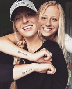 two beautiful young women hugging each other with tattoos on their arms