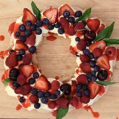 a cake with berries and cream frosting is shown on a wooden surface, surrounded by leaves