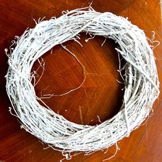 a close up of a wreath on a wooden table with white wire around the edges