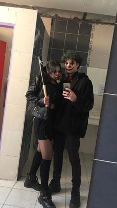 a man and woman standing in front of a bathroom mirror holding an umbrella while looking at their cell phone