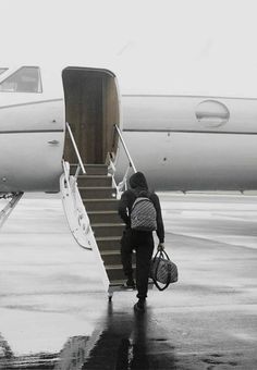 two people walking up the stairs to an airplane with luggage on it's back