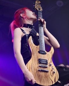 a woman with red hair is holding an electric guitar