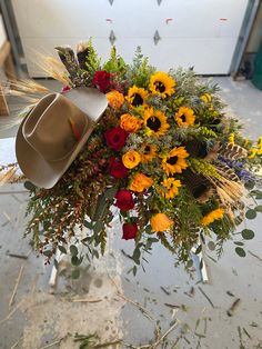 a bouquet of sunflowers and roses with a cowboy's hat on top